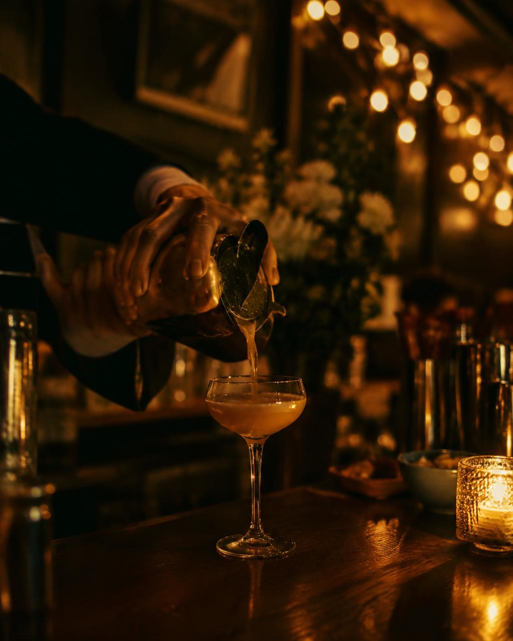 A bartender carefully pouring a fresh cocktail